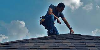 Man on top of roof inspecting shingles